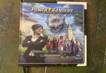 A copy of Power Rangers Beneath The Helmet sitting on a gaming mat.