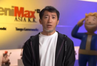 Shinji Mikami speaking in front of a ZeniMax background